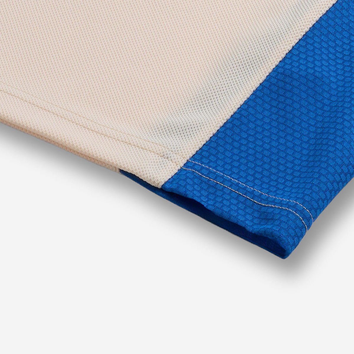 AlphaStyle Reyes Soccer Jersey in Bone – Detailaufnahme des Saums mit blauem Mesh-Seitenpanel