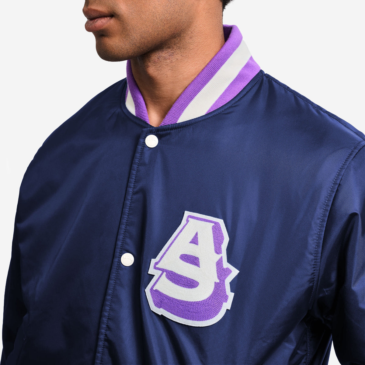 AlphaStyle Barren Varsity Jacket in Navy – Nahaufnahme des AS-Chenille-Patches in Lila und Weiß