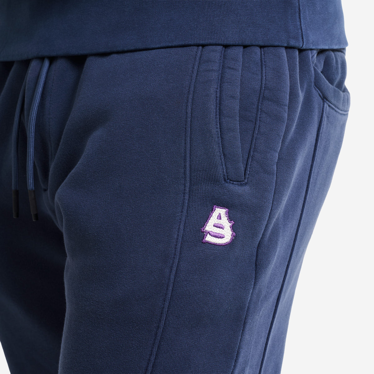 AlphaStyle Tybee Zip Vent Track Pants in Navy – Detailansicht am Model mit Kordelzug-Bund, Eingrifftasche und AS-Stickerei