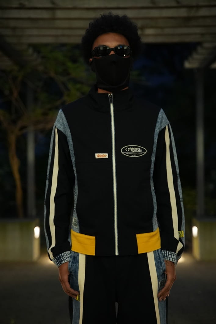 AlphaStyle Lincoln Track Jacket in Black – Frontansicht am Model mit geschlossenem Reißverschluss, Denim-Ärmeln und ovalem Brustlogo